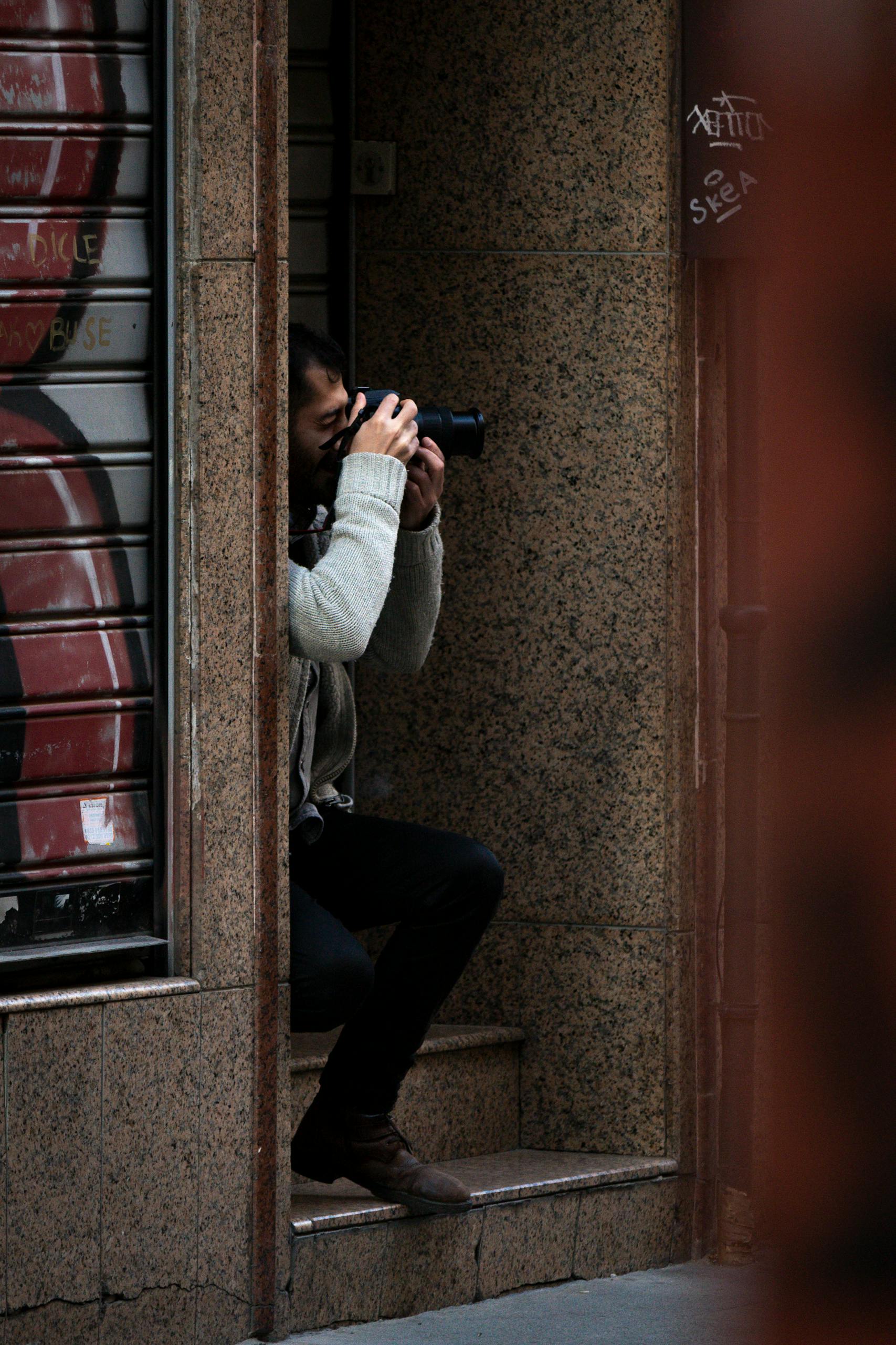 A photographer capturing urban scenes while sitting on city steps.