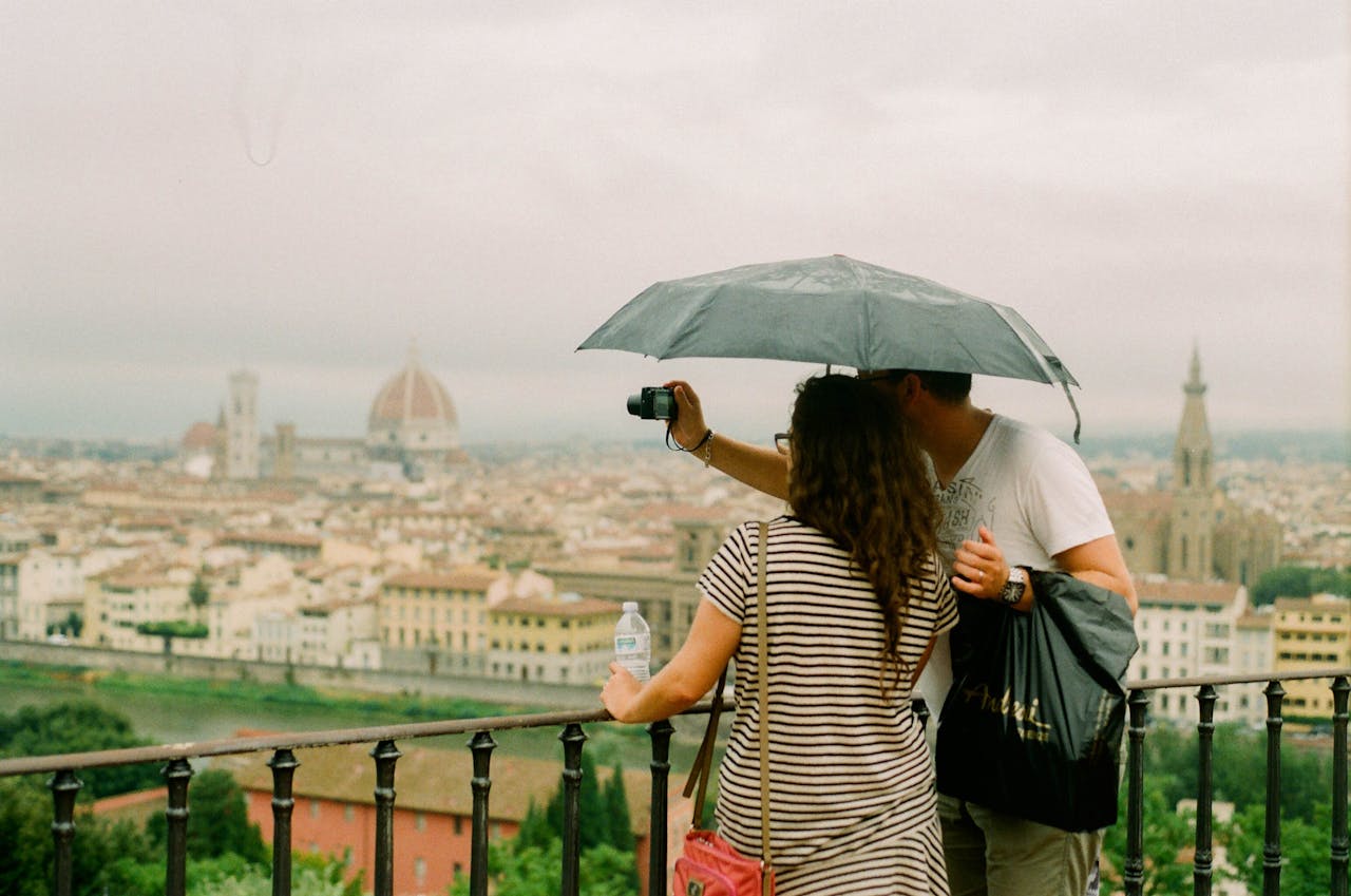 Couple under an umbrella capturing the cityscape of Florence from a scenic viewpoint.