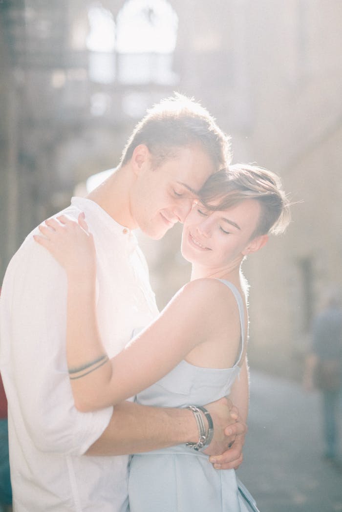 A couple shares a romantic embrace in a sunlit urban environment, exuding warmth and love.