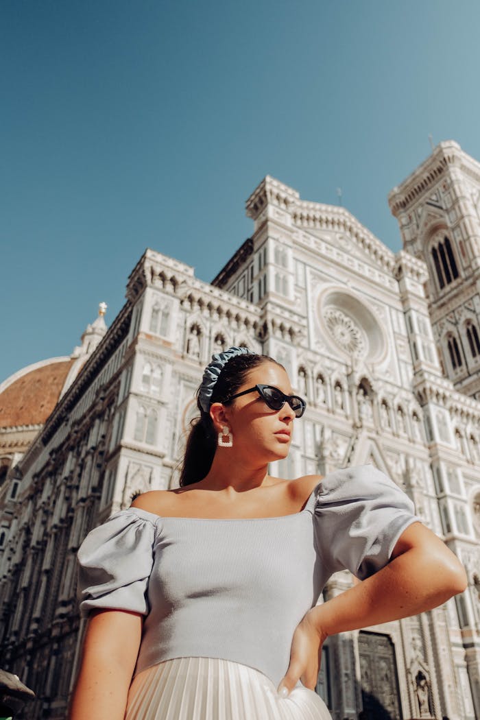 Stylish woman in sunglasses poses in front of the iconic Florence Cathedral on a sunny summer day.